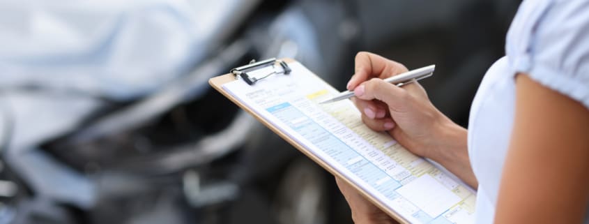 Insurance agent conducts inspection of the damaged car by filling out documents