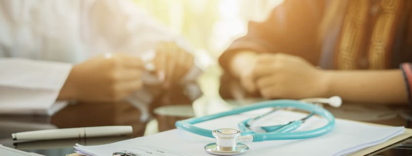 Stethoscope with clipboard and Laptop on desk,Doctor siting across from patient, Healthcare and medical concept