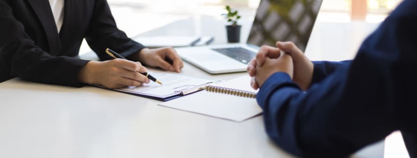 The manager is reading the resume and is interviewing the new employee. Negotiating business and signing a contract. Lawyer and legal advisor.