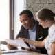 Female financial advisor insurer banker consulting male african american client about contract, caucasian mentor hr and black intern new employee discussing documents at meeting advice